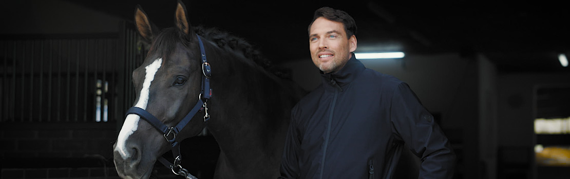Ein Mann in Covalliero Reitsportbekleidung und ein schwarzes Pferd